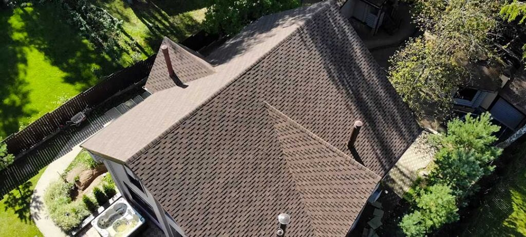 Roofing samples and a rating label beside a sunlit residential roof.